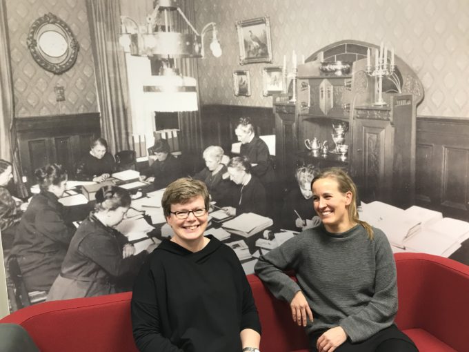 Celian Minna ja Miia istuvat ison historiallisen Celia-valokuvan edessä.