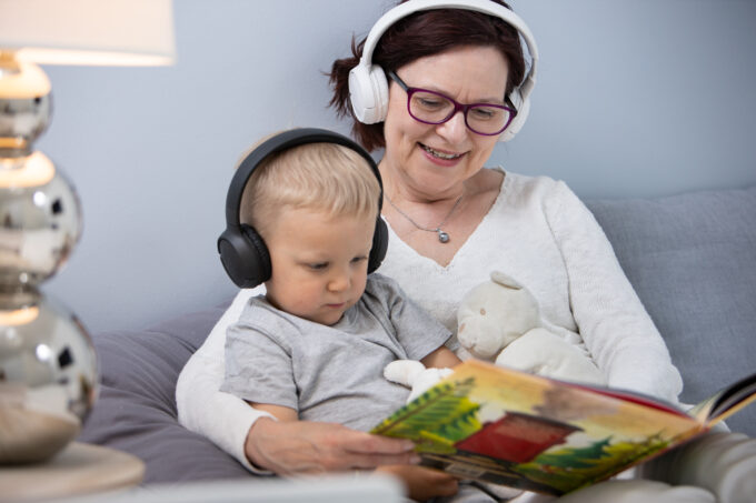 Ett barn tittar och lyssnar på en bok med sin mormor