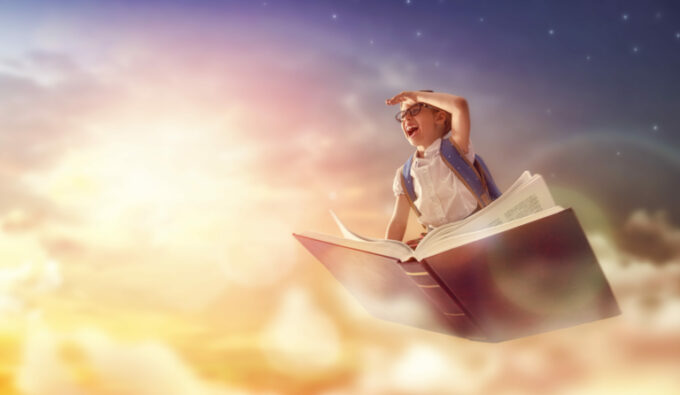 Lapsi lentää taivaalla kirjan päällä, reppu selässään ja eteenpäin tähyten.