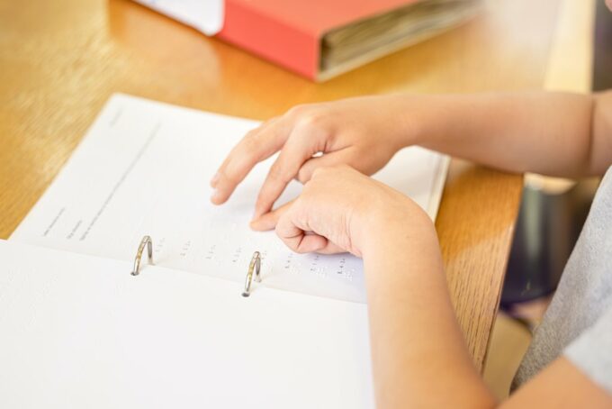 Lapsen kädet lukemassa matematiikan pisteoppikirjaa.