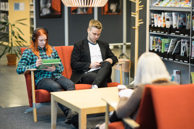 ihmisiä istuu kirjaston penkillä. <a href="https://www.celia.fi/saavutettavuus">Celian sivut</a>